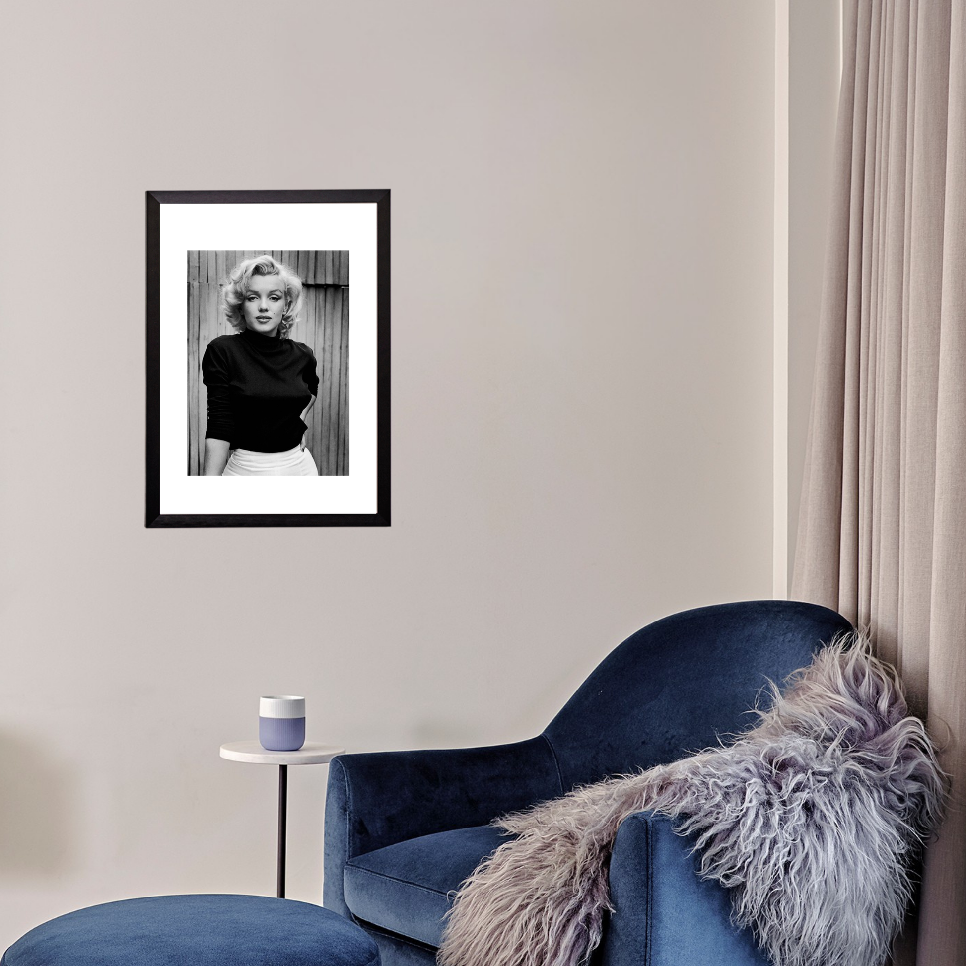 Framed black and white portrait of a woman on a wall above a blue armchair with a fur throw.