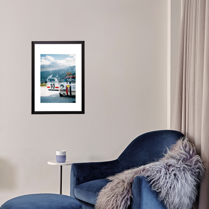 Framed picture of a race car on a wall above a blue armchair with a fur throw.