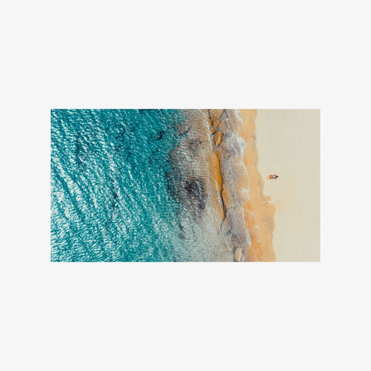 Top-down view of a beach with blue water and sand.