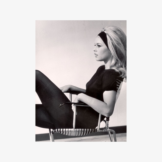 Black and white photo of a woman sitting on a modern chair.
