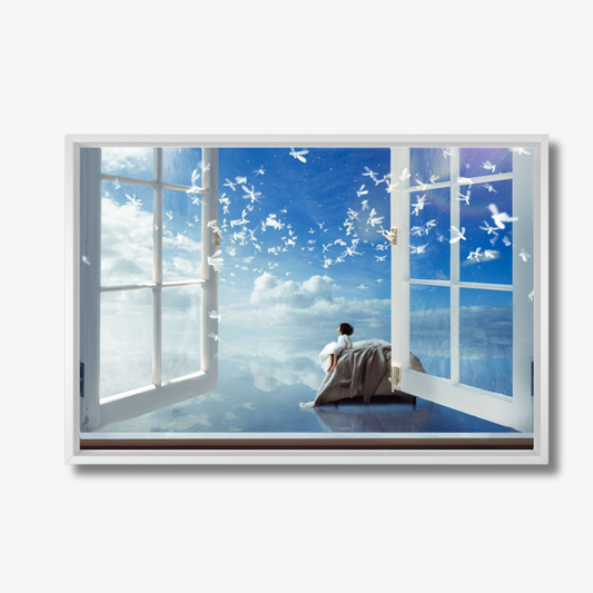 Person sitting on a bed looking out of an open window at a blue sky with clouds.