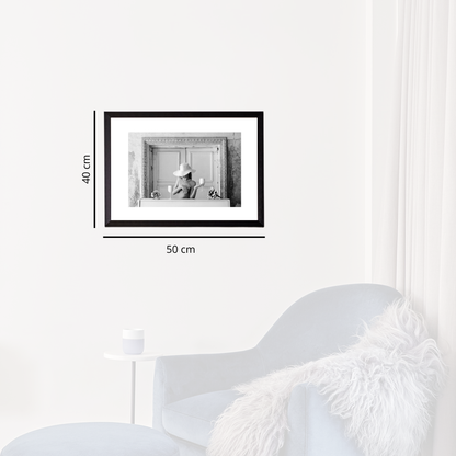 Framed black and white photo on a white wall with dimensions indicated