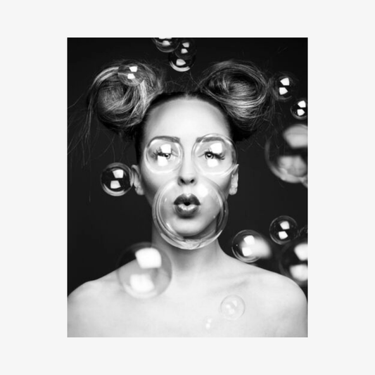Black and white photo of a person blowing bubbles with a dark background