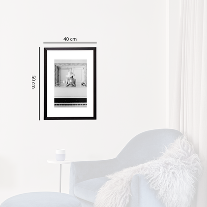 Framed black and white photo on a white wall with dimensions indicated