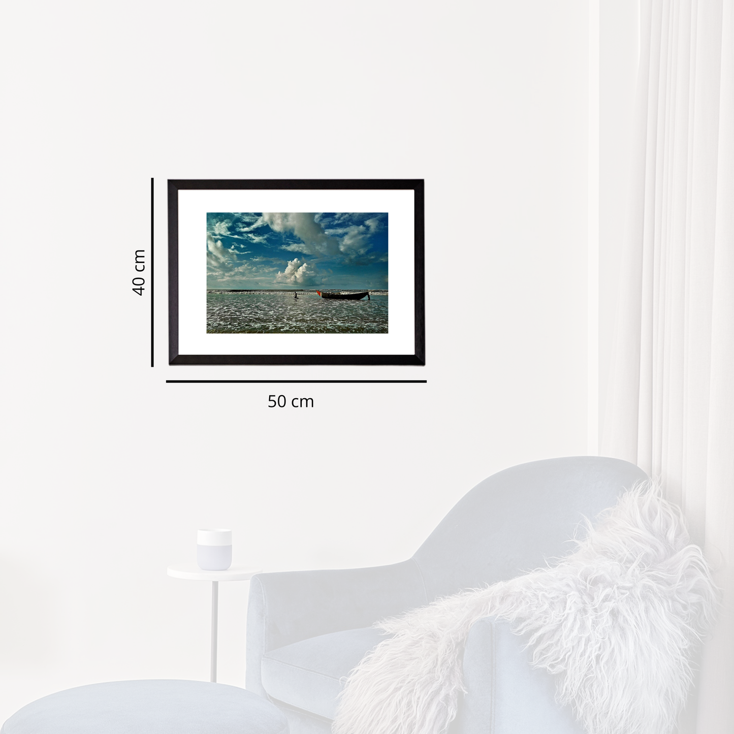 Framed artwork of a beach scene with a boat, displayed on a white wall.