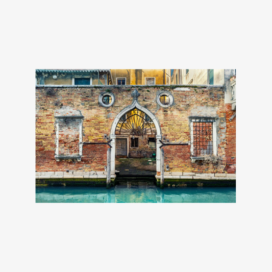 Archway over a canal with brick building in Venice