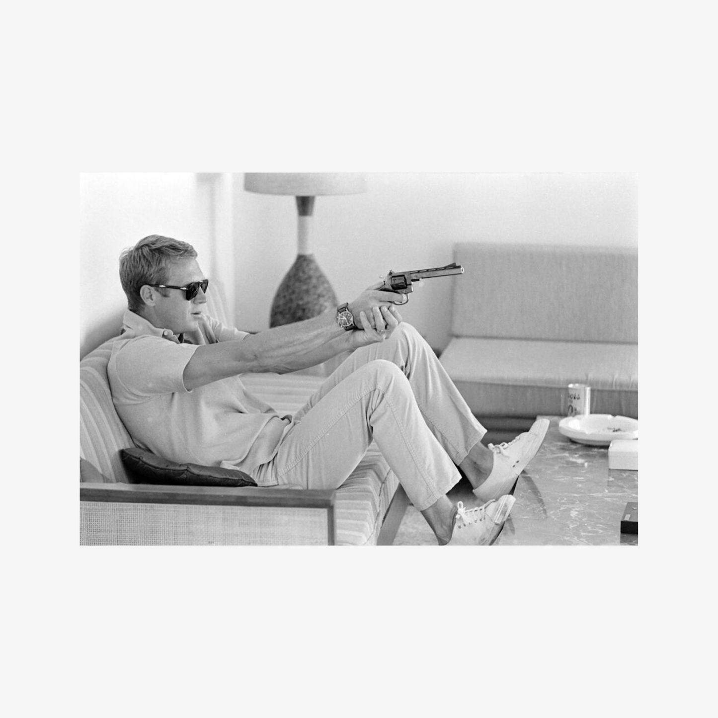 Man sitting on a couch holding a gun in a black and white photo