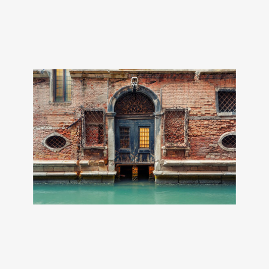 Traditional Venetian building with arched door and windows, partially submerged in water.