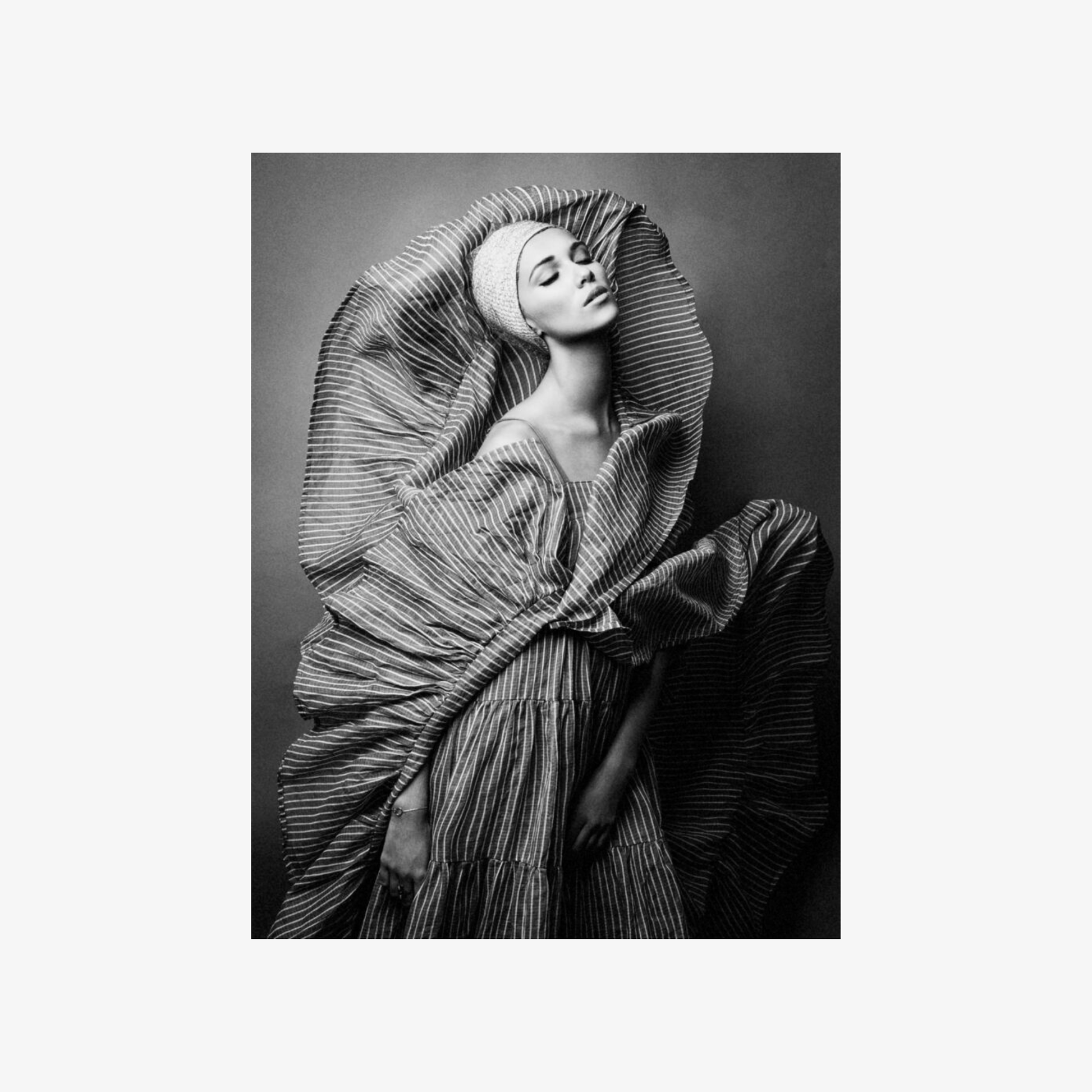 Black and white fashion photograph of a model wearing a textured dress with a draped effect.
