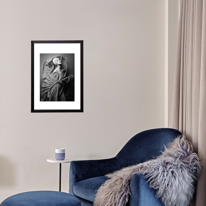 Framed artwork on a wall above a blue armchair with a fur throw.