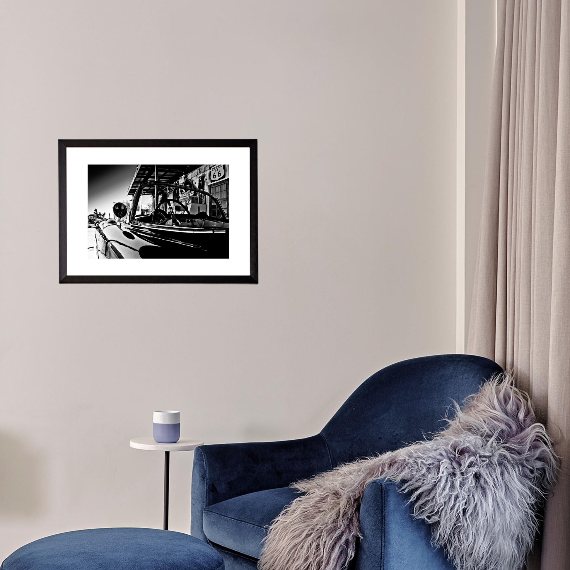 Framed black and white photograph on a wall above a blue armchair with a fur throw.