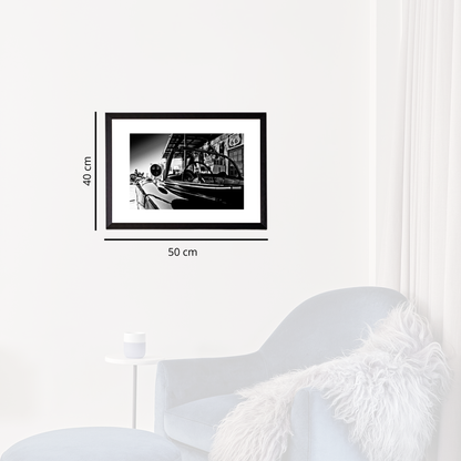 Framed black and white photo on a wall next to a white chair