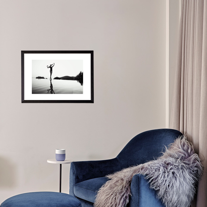 Framed black and white artwork on a wall above a blue armchair with a fur throw.