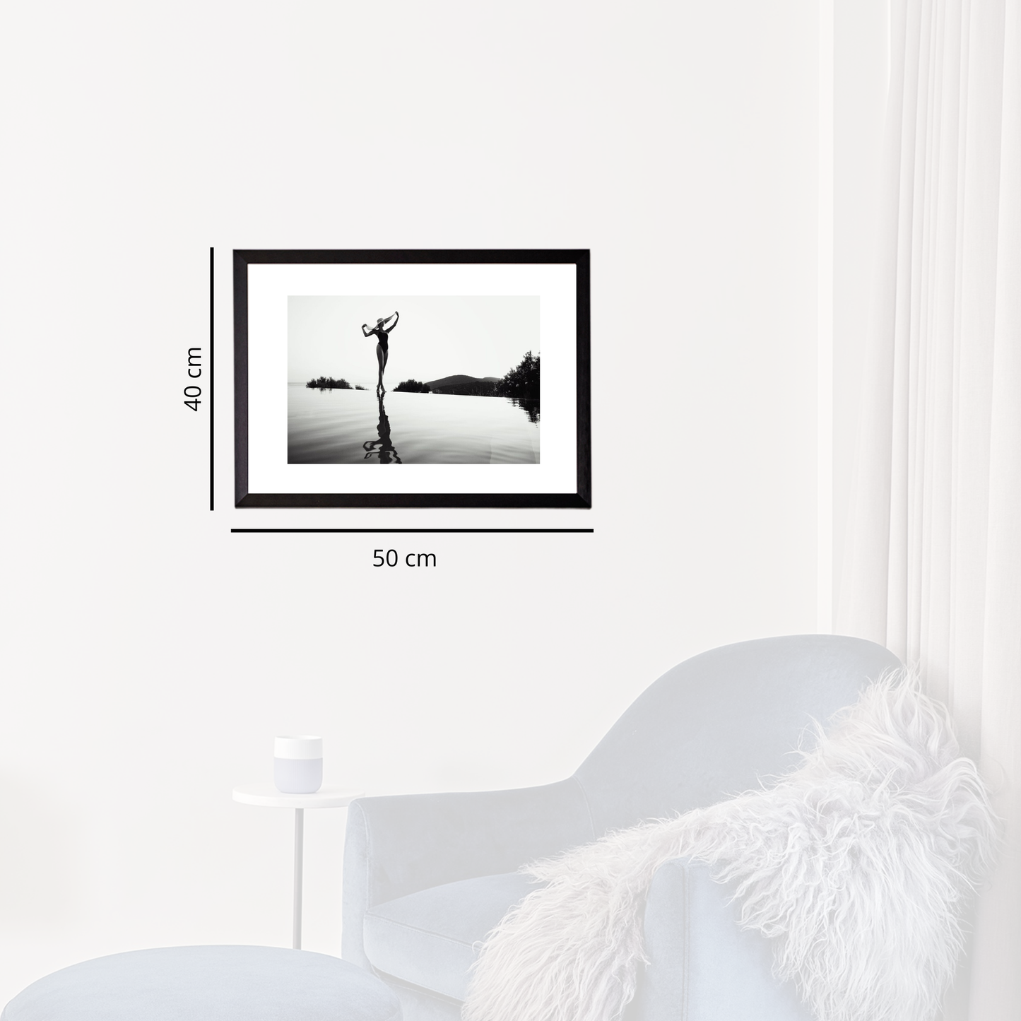 Framed black and white artwork on a wall next to a white chair.