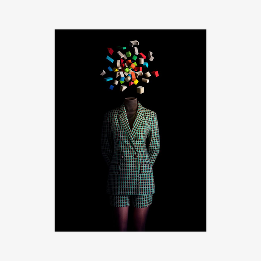 Mannequin wearing a green checkered outfit with colorful geometric shapes above its head on a black background
