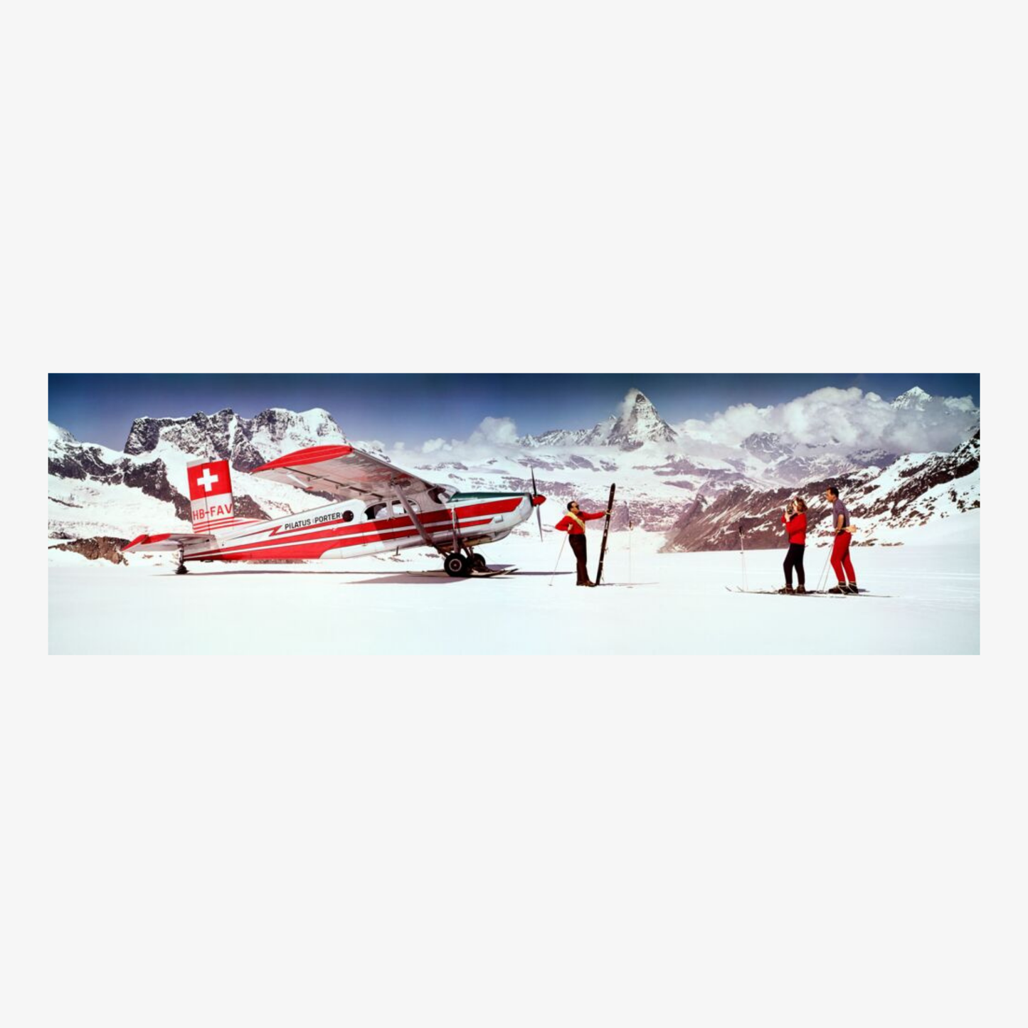 Small red and white airplane on a snowy mountain with people nearby