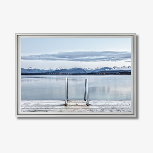 Framed photograph of a dock extending into a lake with mountains in the background.