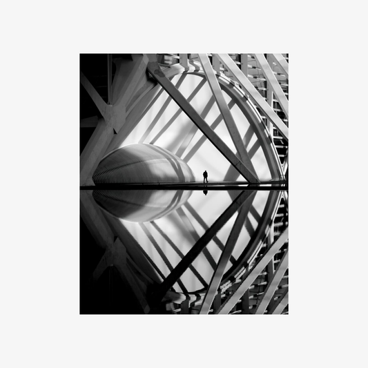 Black and white reflection of a person standing on a reflective surface with architectural elements.