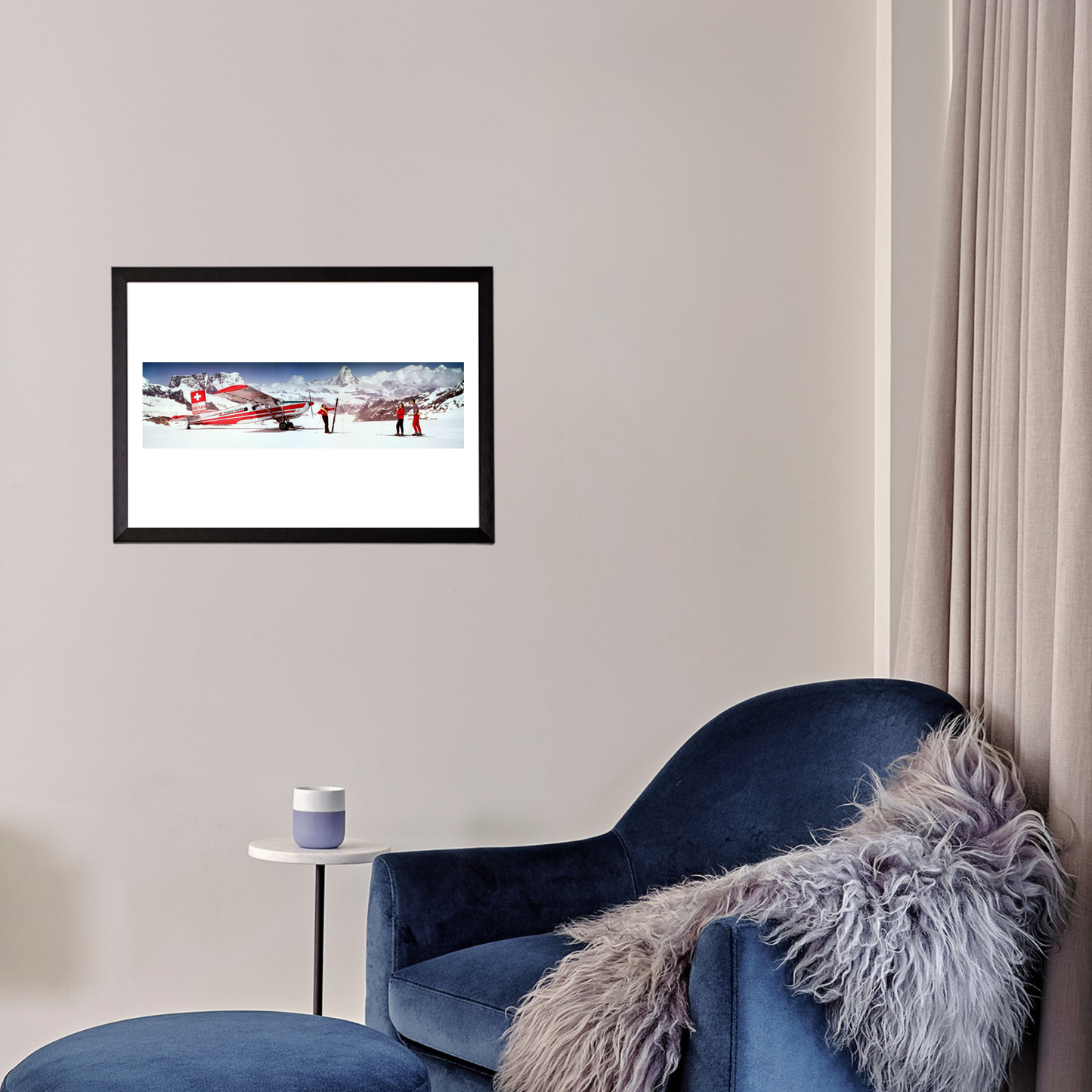 Framed picture of a red airplane on a snowy landscape above a blue armchair with a fur throw.