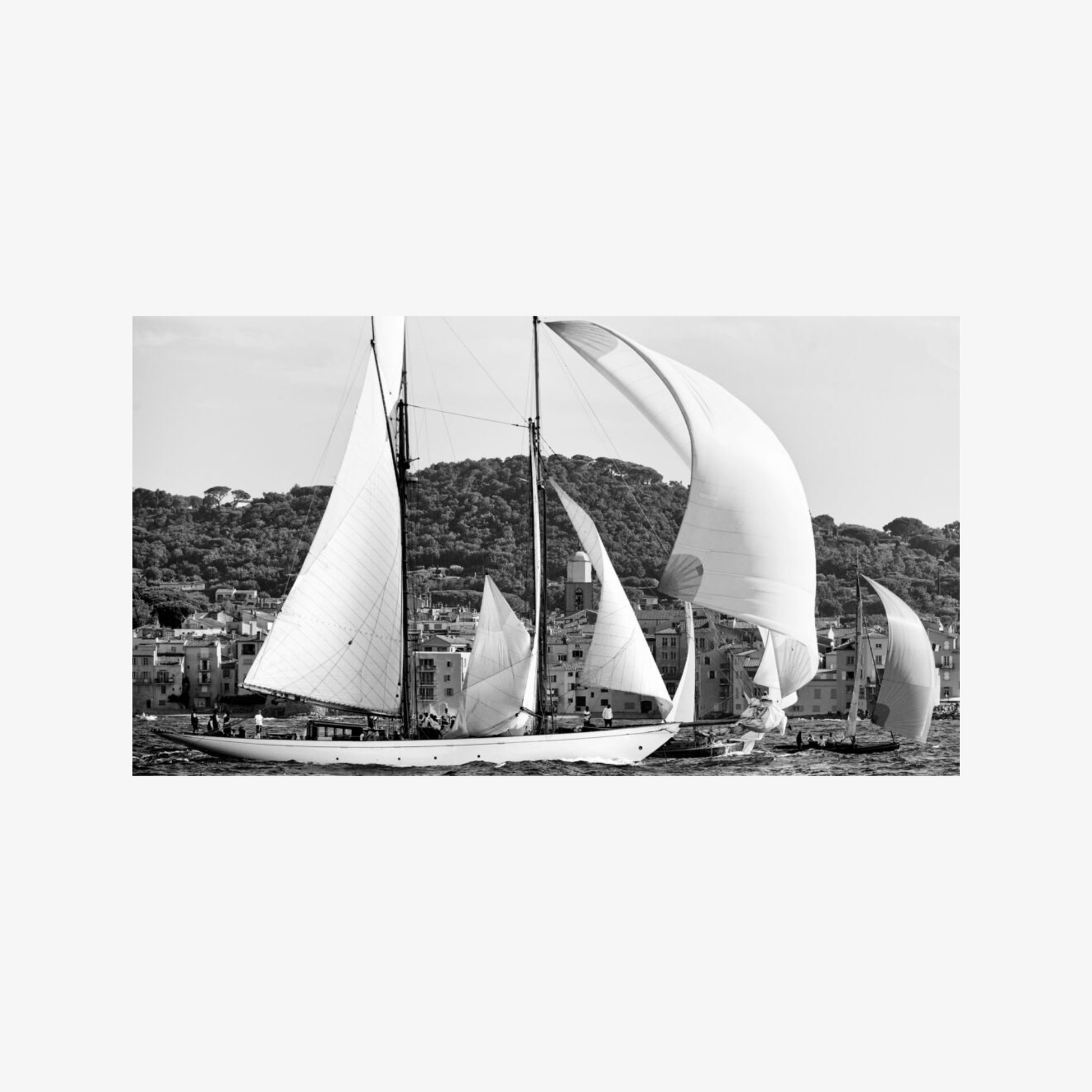 Black and white image of sailboats on a body of water with a scenic background.