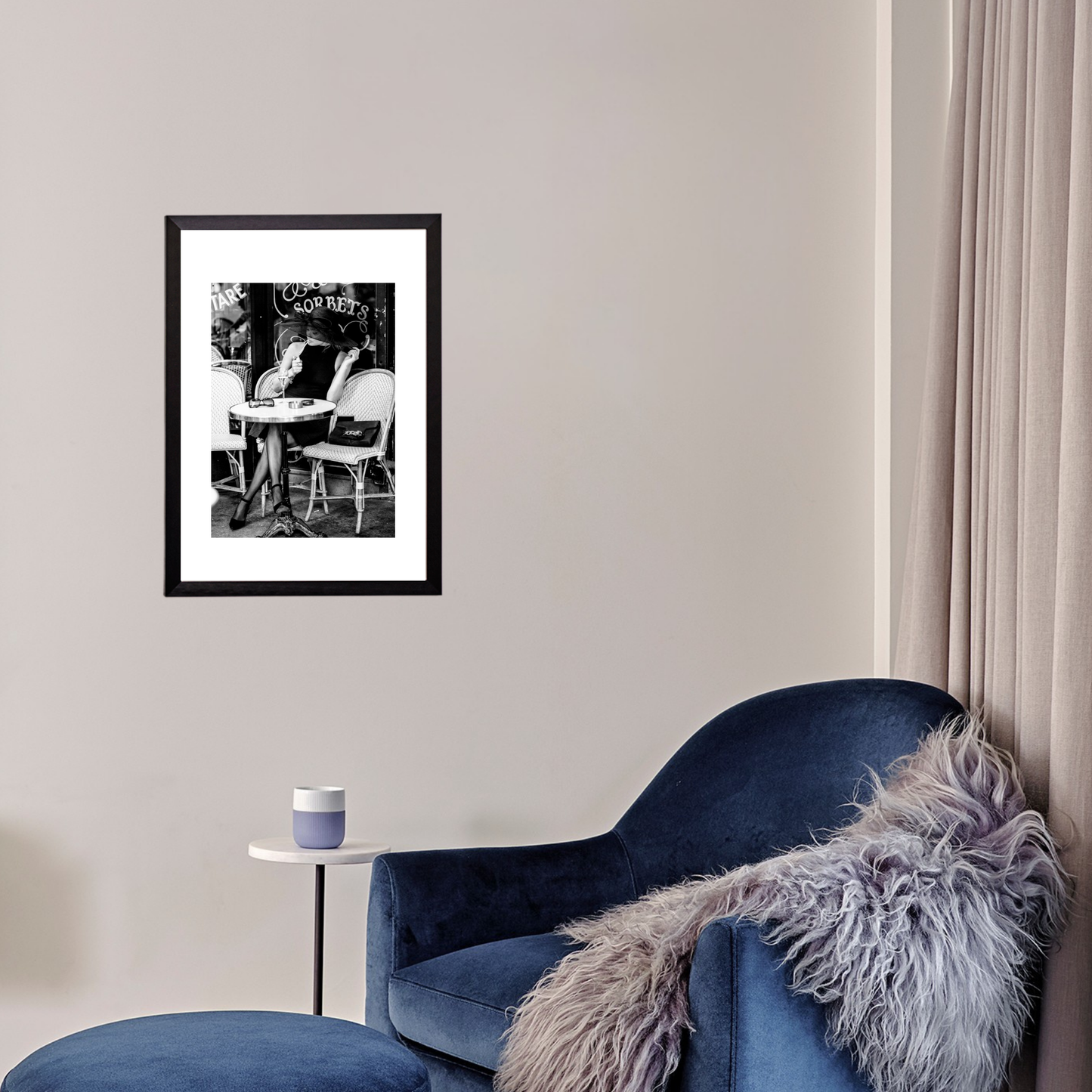 Blue armchair with a fur throw next to a framed black and white print on a wall.