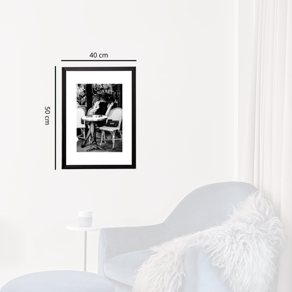 Framed black and white photo on a white wall with dimensions indicated