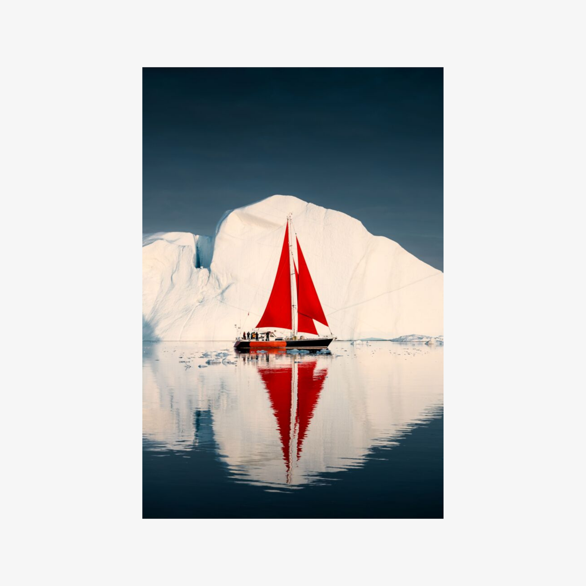 Sailboat with a red sail on a calm lake with icebergs in the background