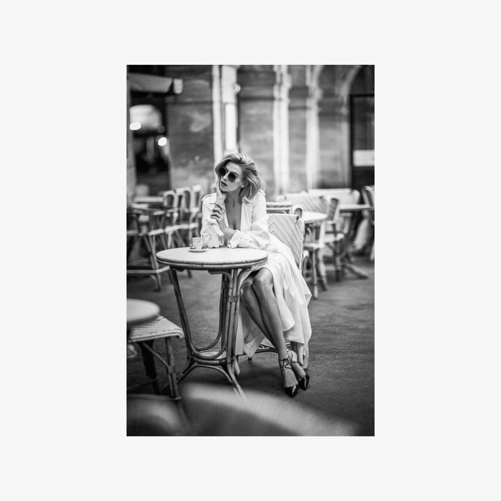 Woman sitting at a table in an outdoor cafe, black and white photo