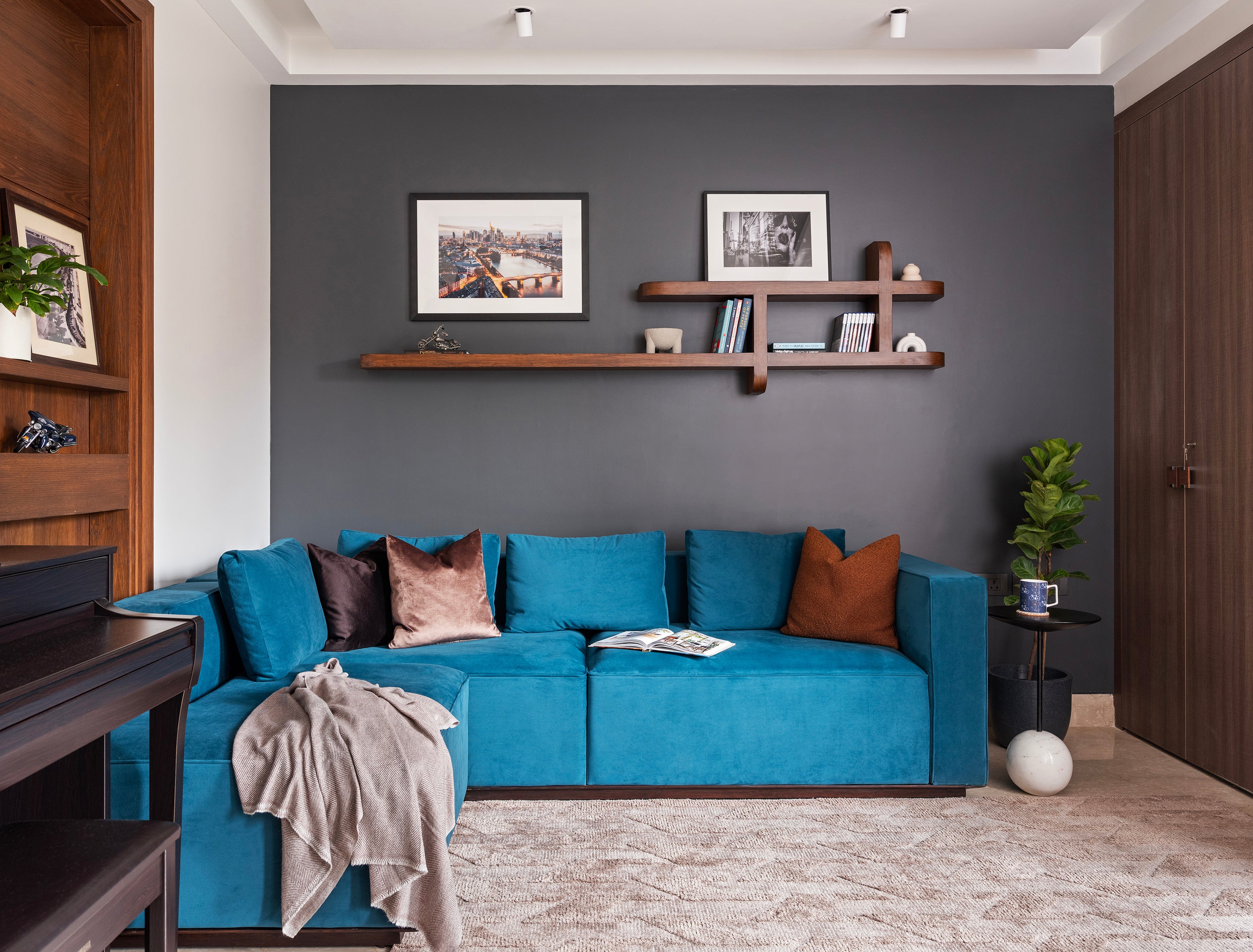 Modern living room with a blue sofa, wooden shelves, and decorative items.